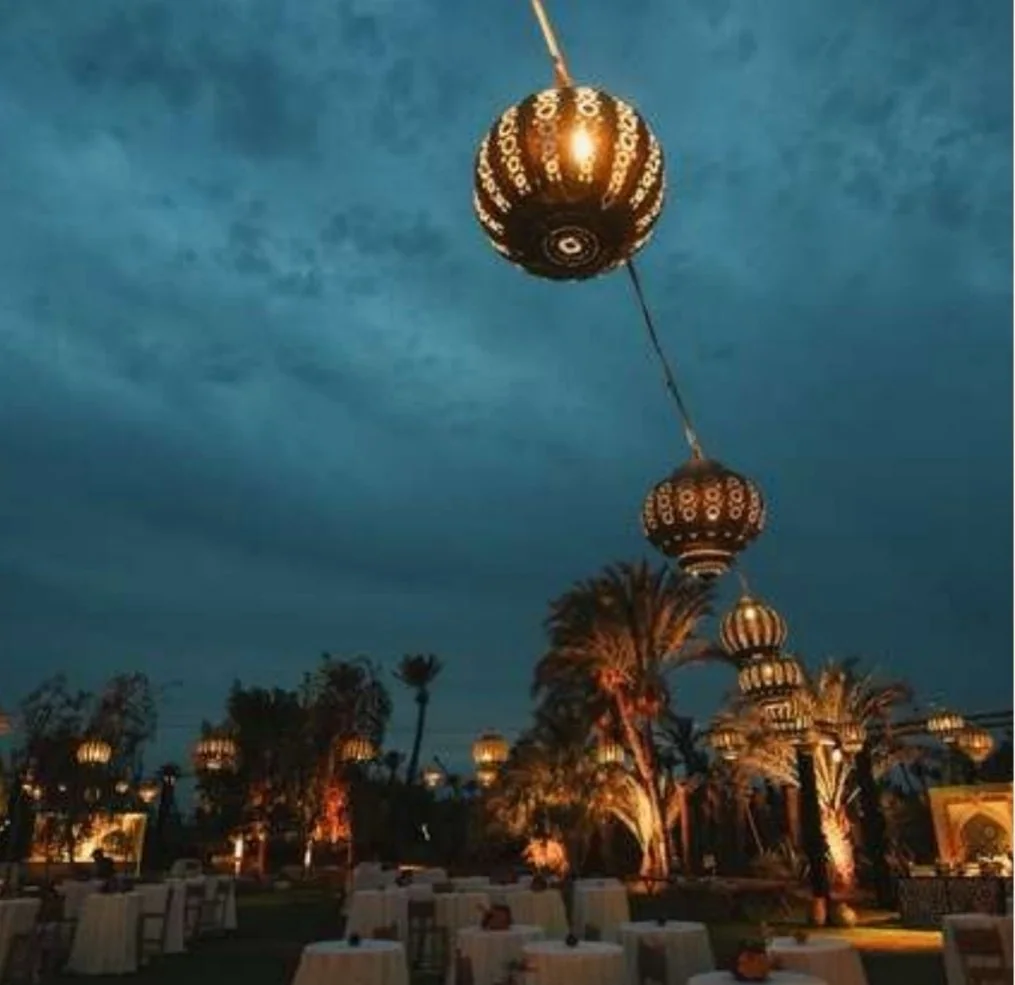 Lanternes marocaines allumées au-dessus d’un dîner dans les jardins, au crépuscule